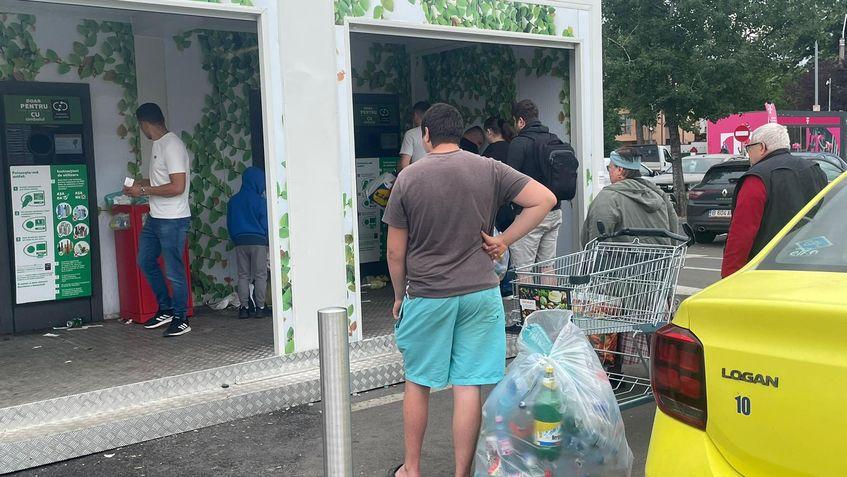 În parcarea unui hypermarket din București au fost amplasate mai multe automate de colectare a ambalajelor cu sigla SGR, iar oamenii așteaptă la coadă pentru a-și recupera garanția de 50 de bani. Foto: Laura Popa 