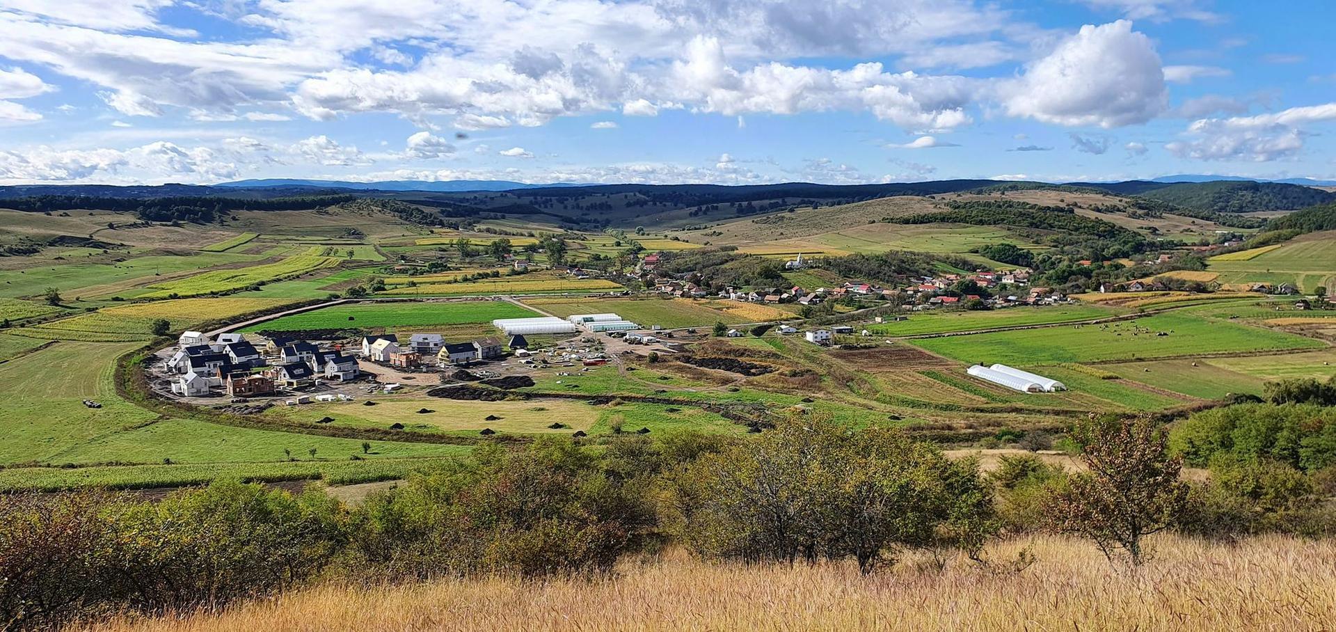 Un teren de 140 de hectare care include dealurile dimprejur, de pe care este făcută această fotografie. Orășelul va fi situat în vale, dar unele case vor avea și o vedere panoramică asupra văii.