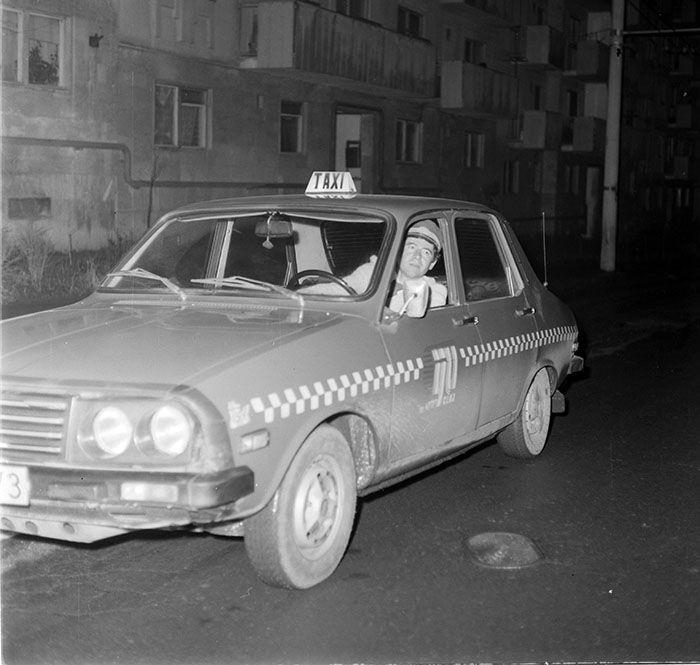 Taximetriștii din toată țara aveau o uniformă specifică, la care s-a renunțat după 1990. Foto: taximetru din Cluj-Napoca, <a target="_blank" rel="noreferrer noopener" href="http://www.photoarchive.minerva.org.ro/Ro/search?query=taxi" target="_blank">Arhiva Foto Minerva</a>
