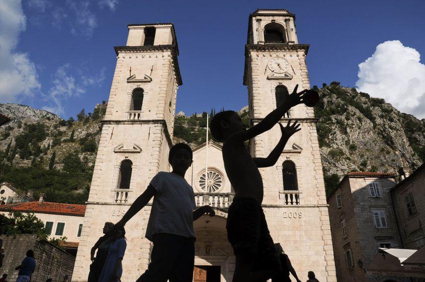 Siluetele unor copii se conturează pe fundalul catedralei romano-catolice Sfântul Trifon din Kotor.