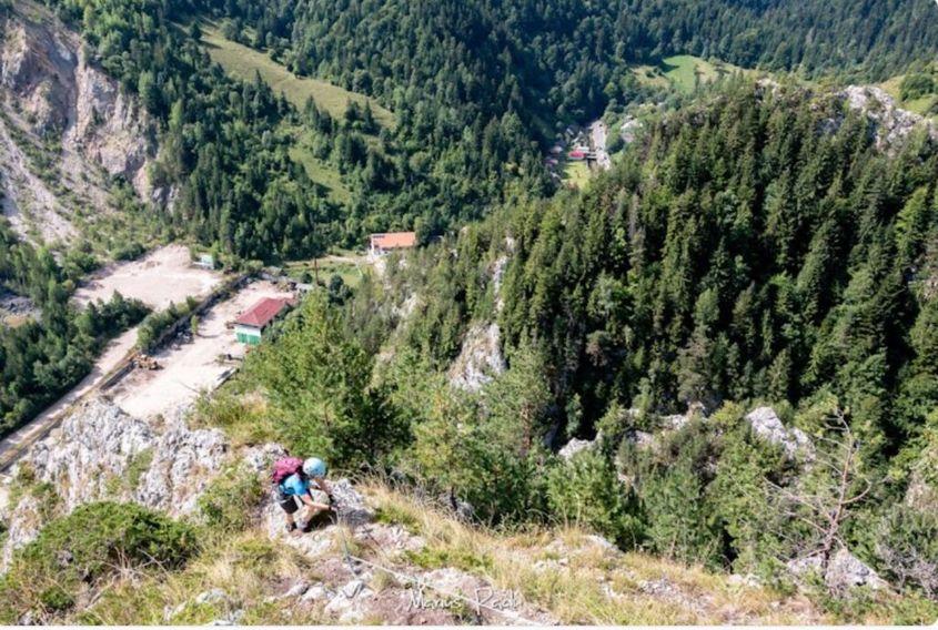 Traseu de cățărat în Rezervația Cheile Șugăului. Pot fi văzute jos în vale cabana Ecolog și parcarea carierei de piatră. Foto: Cabana Ecolog