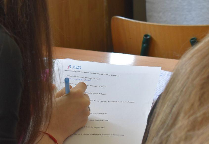 O elevă de clasa a cincea calculează dobânda unei sume depuse la bancă. Foto: Lavinia Niță / PressOne 