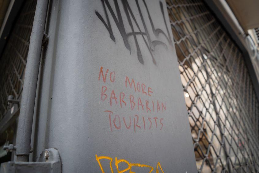 „Nu mai vrem turiști barbari.” Semn în cartierul Koukaki din Atena, unul dintre cartierele care suferă cel mai rău din cauza turistificării și gentrificării. Foto: Ioana Epure