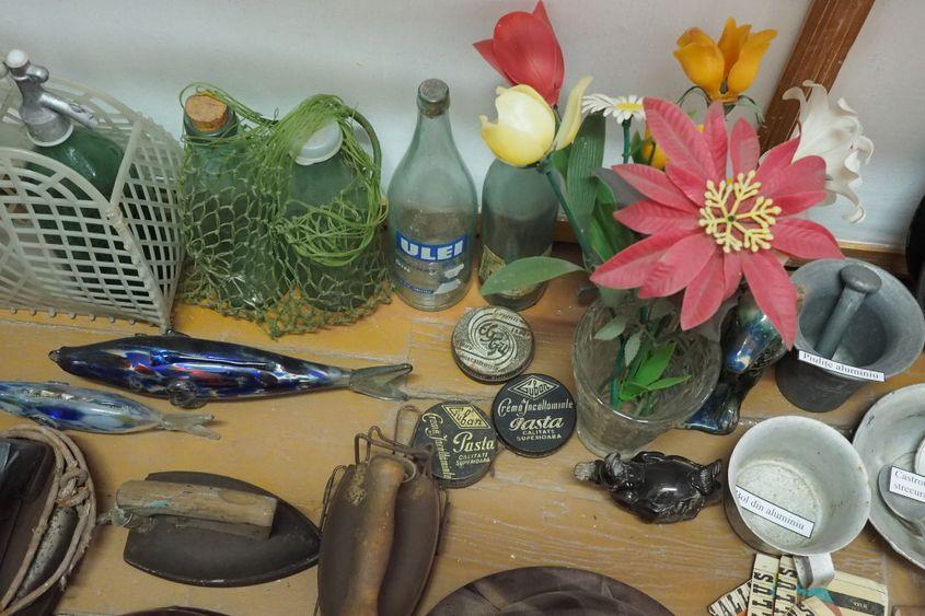 Obiecte din comunism: sticle de sifon, lapte și ulei, flori de plastic, boluri de aluminiu, cremă de ghete, fiare de călcat și celebrii pești de sticlă. Foto: Voicu Bojan