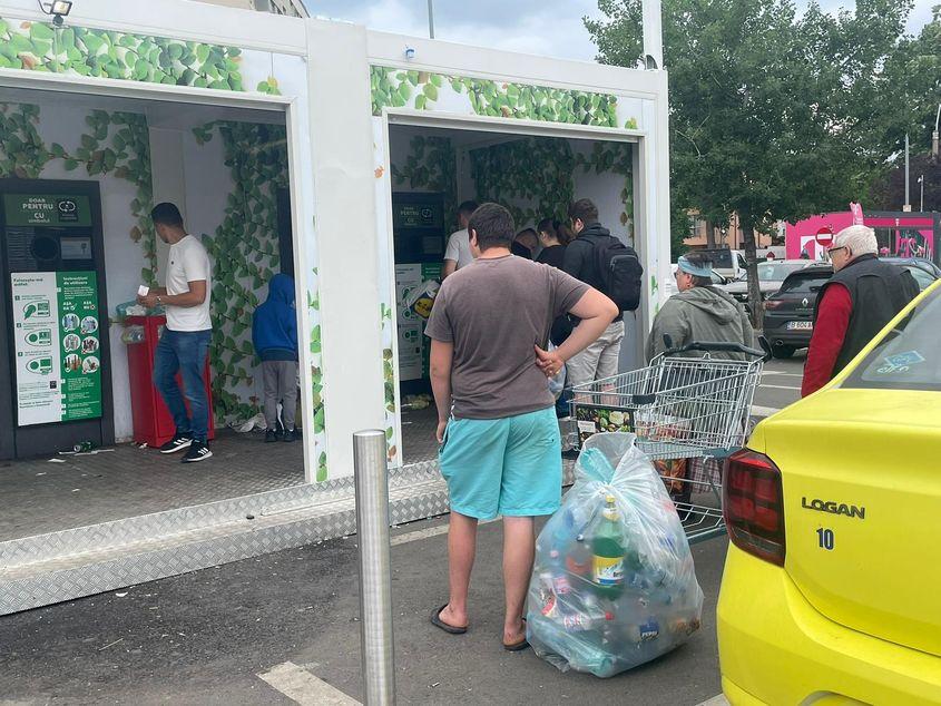 În parcarea unui hypermarket din București au fost amplasate mai multe automate de colectare a ambalajelor cu sigla SGR, iar oamenii așteaptă la coadă pentru a-și recupera garanția de 50 de bani. Foto: Laura Popa 