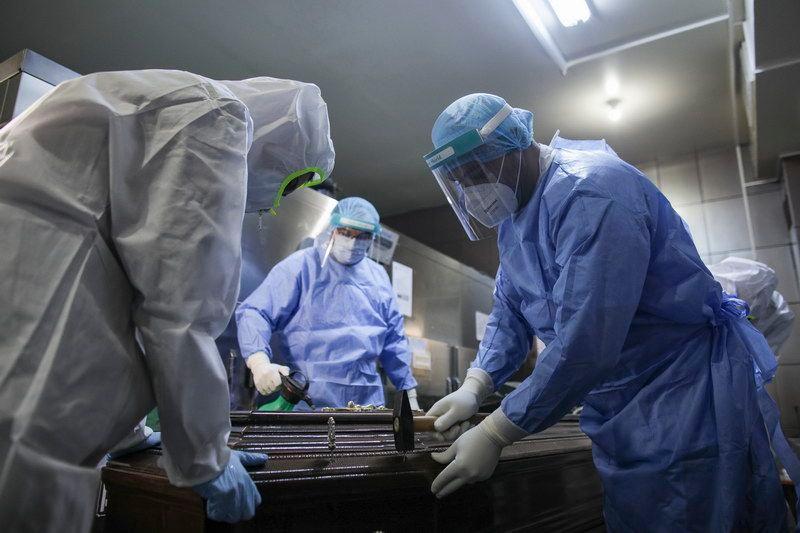 „Medici anatomopatologi și lucrători la pompe funebre închid un coșciug al unui bolnav de COVID-19, la morga Spitalului Universitar, București.” <em>Inquam Photos / Octav Ganea</em>