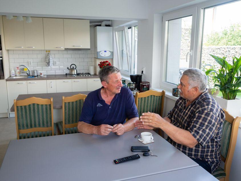 Doi dintre musafirii Casei Filip, discutând în bucătărie.