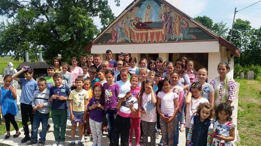 Copii din Lada, alături de preotul Danu, în fața bisericii din sat. Sursa foto: mana-cereasca.ro