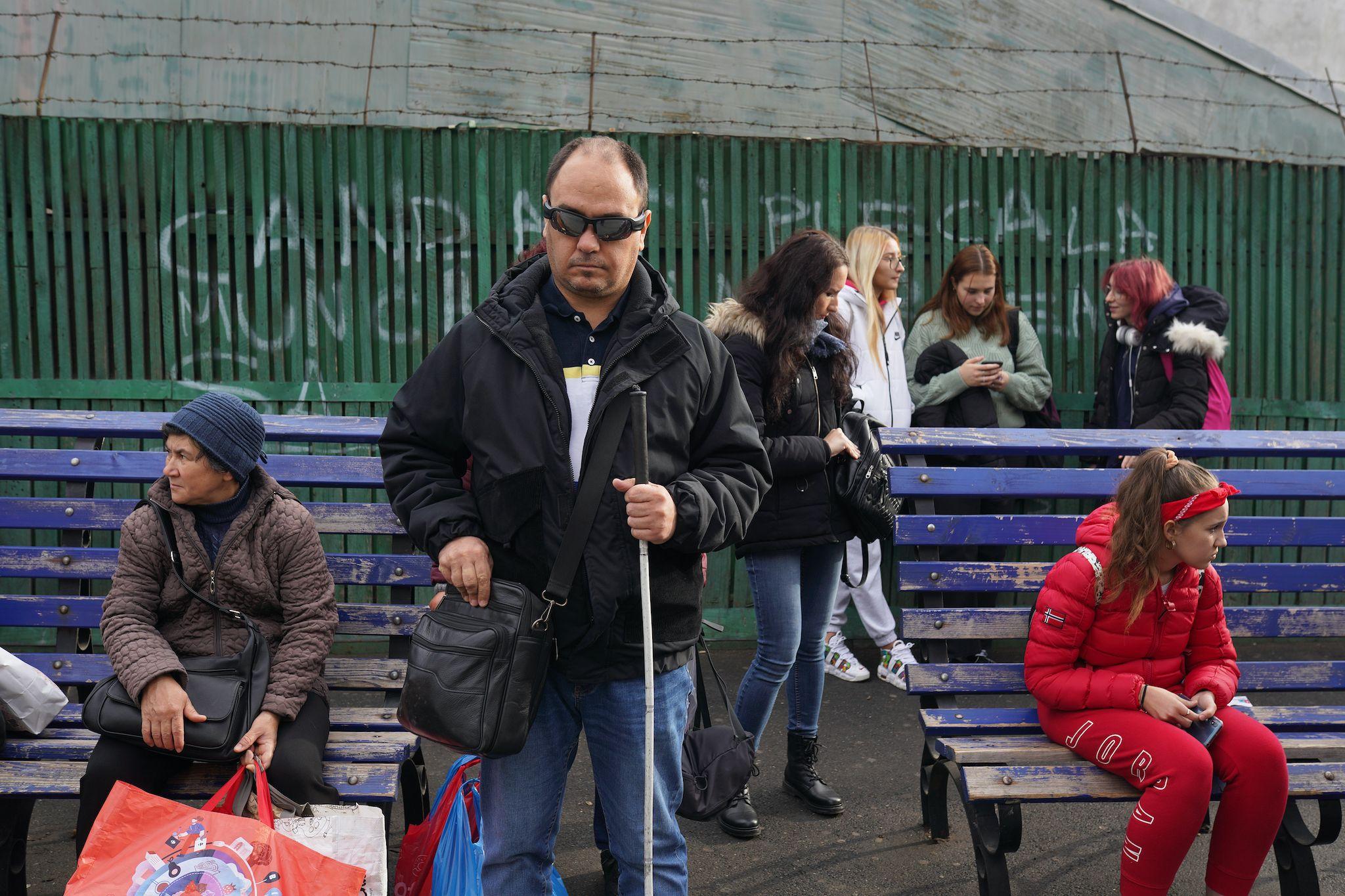 Ionuț așteaptă în stația de autobuz, în timpul unui traseu obișnuit pentru el, pentru a arăta cât de dificil e să se miște prin București, pe 18 noiembrie 2022. Foto: Andreea Câmpeanu