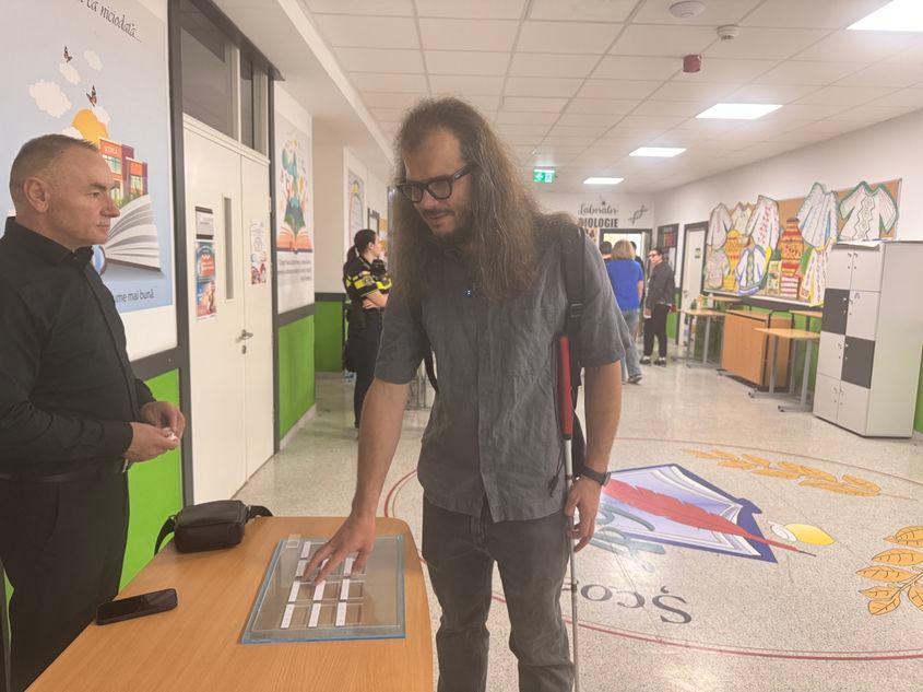 Alexandru se obișnuiește cu șablonul pe care-l va folosi pentru a putea vota. Foto: Laura Popa