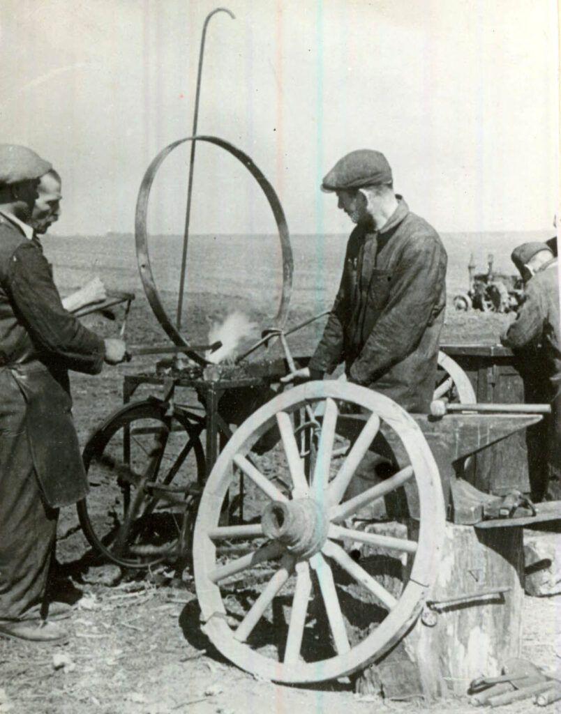 O echipă de muncitori veniţi din uzine, pe tarlalele ţăranilor muncitori, repară uneltele agricole ajutându-i în campania însămânţărilor, martie 1945. Fototeca IICCMER (c)