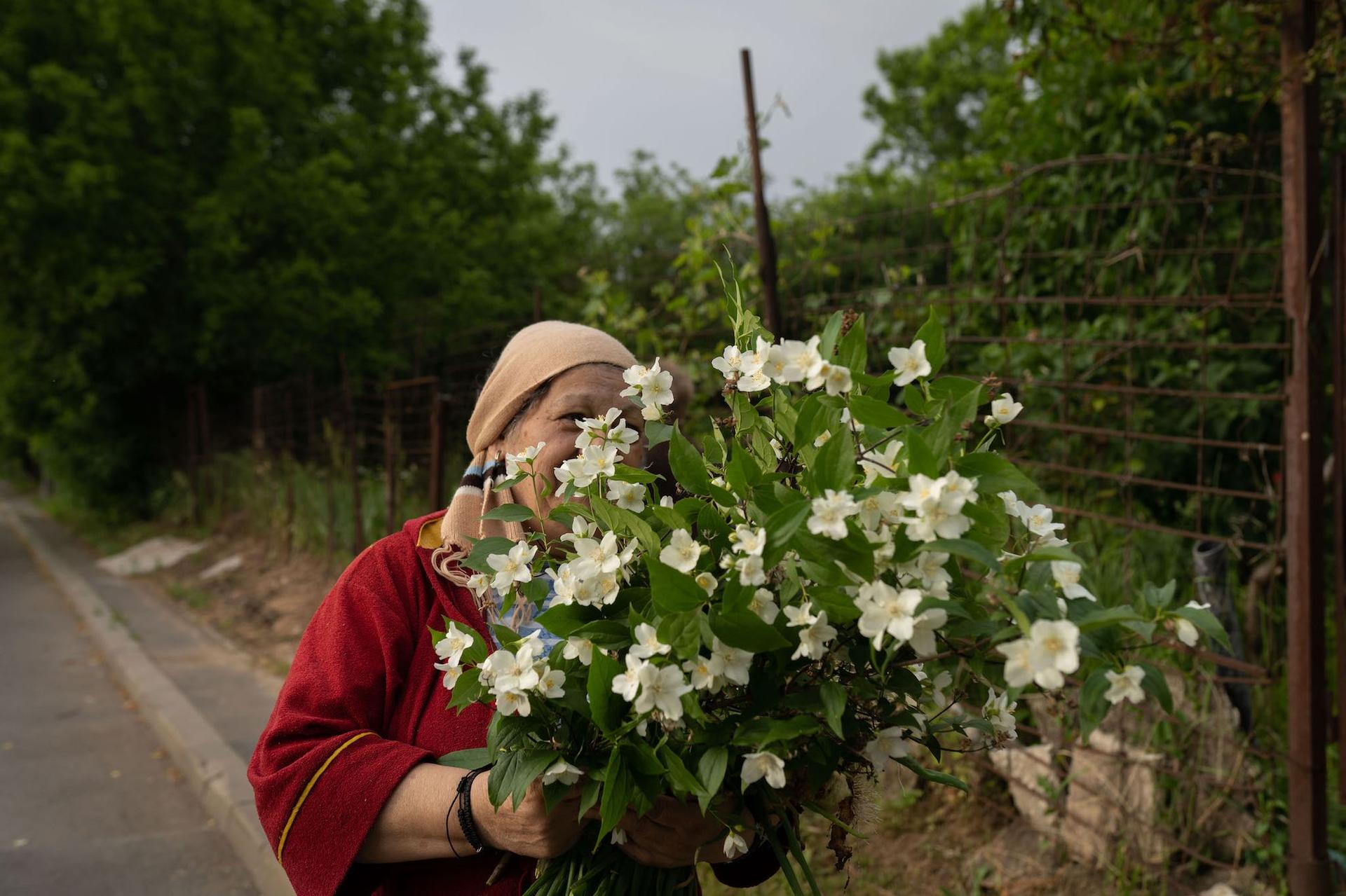O femei ține un buchet de flori în mână, lângă calea ferată abandonată, pe <em>Strada Șinei</em>. Foto: Andreea Câmpeanu