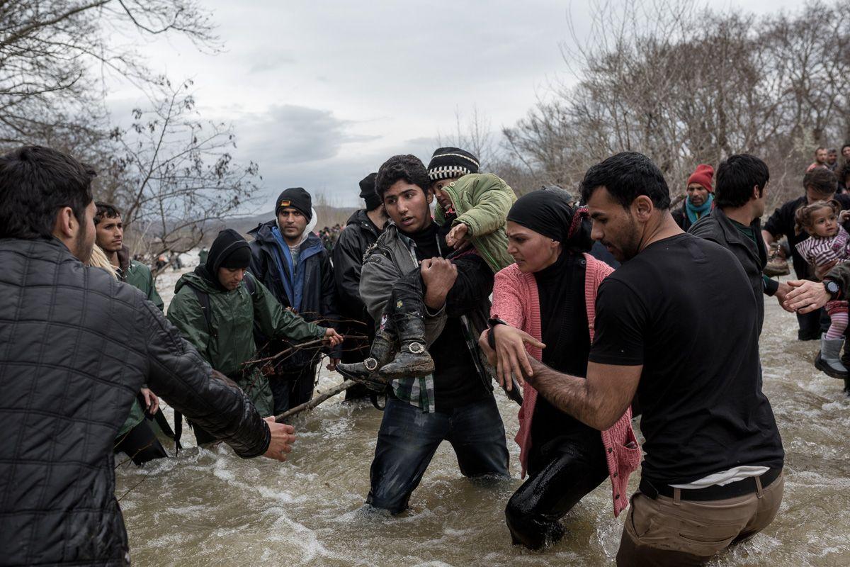 Migranți se ajută reciproc în încercarea de a traversa râul Malarekas, în apropiere de satul Chamilo, de lângă granița cu Macedonia de Nord, 14 martie 2016. Foto: Konstantinos Tsakalidis