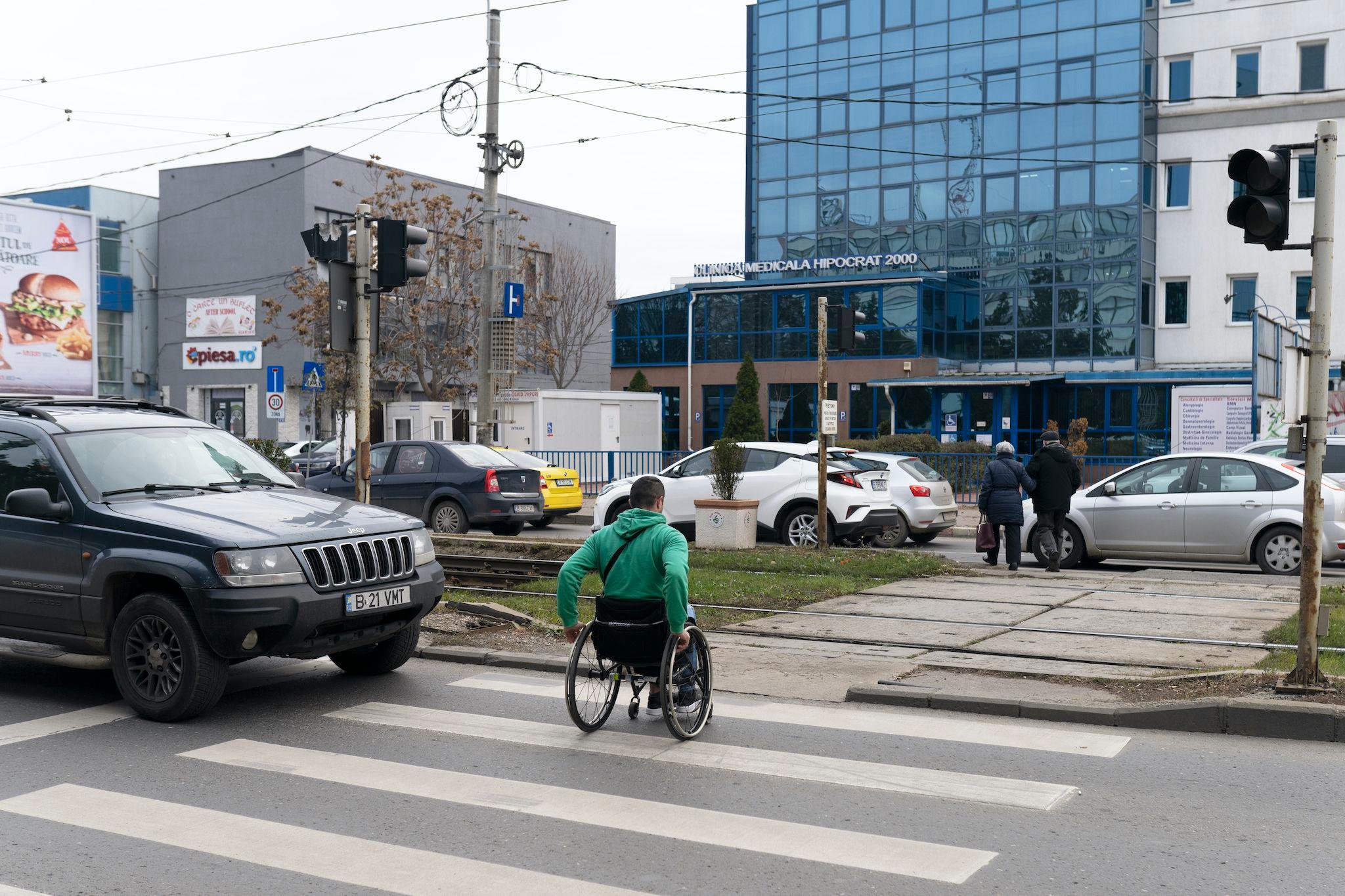 Angel Moraru, care se deplasează în scaun rulant, demonstrează cum se poate mișca pe o stradă din București. Sau, mai degrabă, care sunt obstacolele. Foto: Andreea Câmpeanu