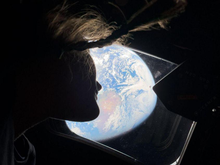 Astronauta NASA și specialistă a misiunii Artemis II, Christina Koch, privește prin unul dintre hublourile principale ale capsulei Orion, uitându-se înapoi spre Pământ, în timp ce echipajul călătorește către Lună. Foto: NASA