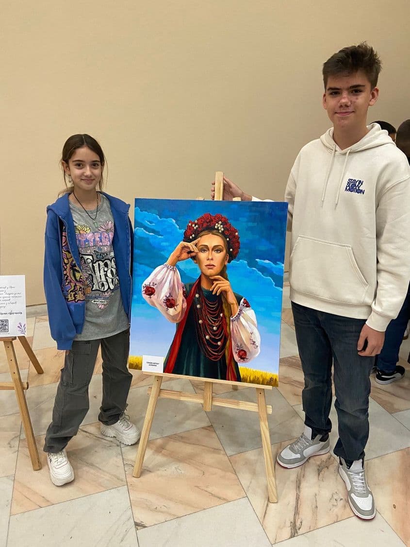 Konstantyn, alături de o colegă din Child Advisory Board, (o structura consultativă menită să-i ajute pe copii și pe tineri să se implice în luarea deciziilor). Fotografiile sunt realitate la evenimentul „Gala Premiilor Dreptului Copilului J. Korczak”, organizat în decembrie 2022 la București, pentru tineri români și ucraineni. Pictura este parte a unei expoziții de pictură ale tinerilor/copiilor din Ucraina. Foto: Centrul pentru Resurse Civice Constanța