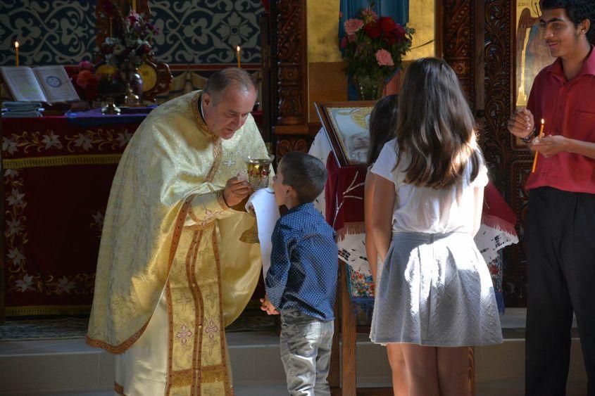 Copiii din Moșuni și din Veța primesc împărtășania de la preotul Mihai Hăbălău. Foto: Viorel Ilișoi