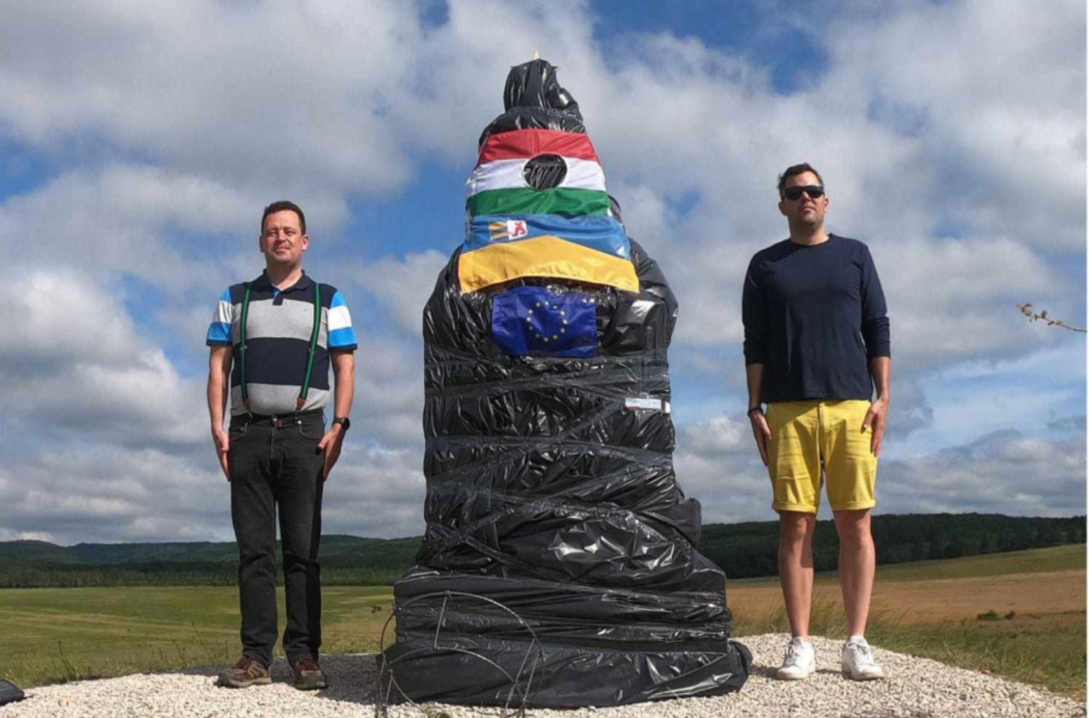 Monumentul din Csákberény, protest după inaugurare. Protestatarii l-au învelit în plastic negru, au adăugat simbolul Revoluției din 1956 - un steag maghiar cu o gaură în el — precum și un steag ucrainean și unul al Uniunii Europene. Sursă foto: 444