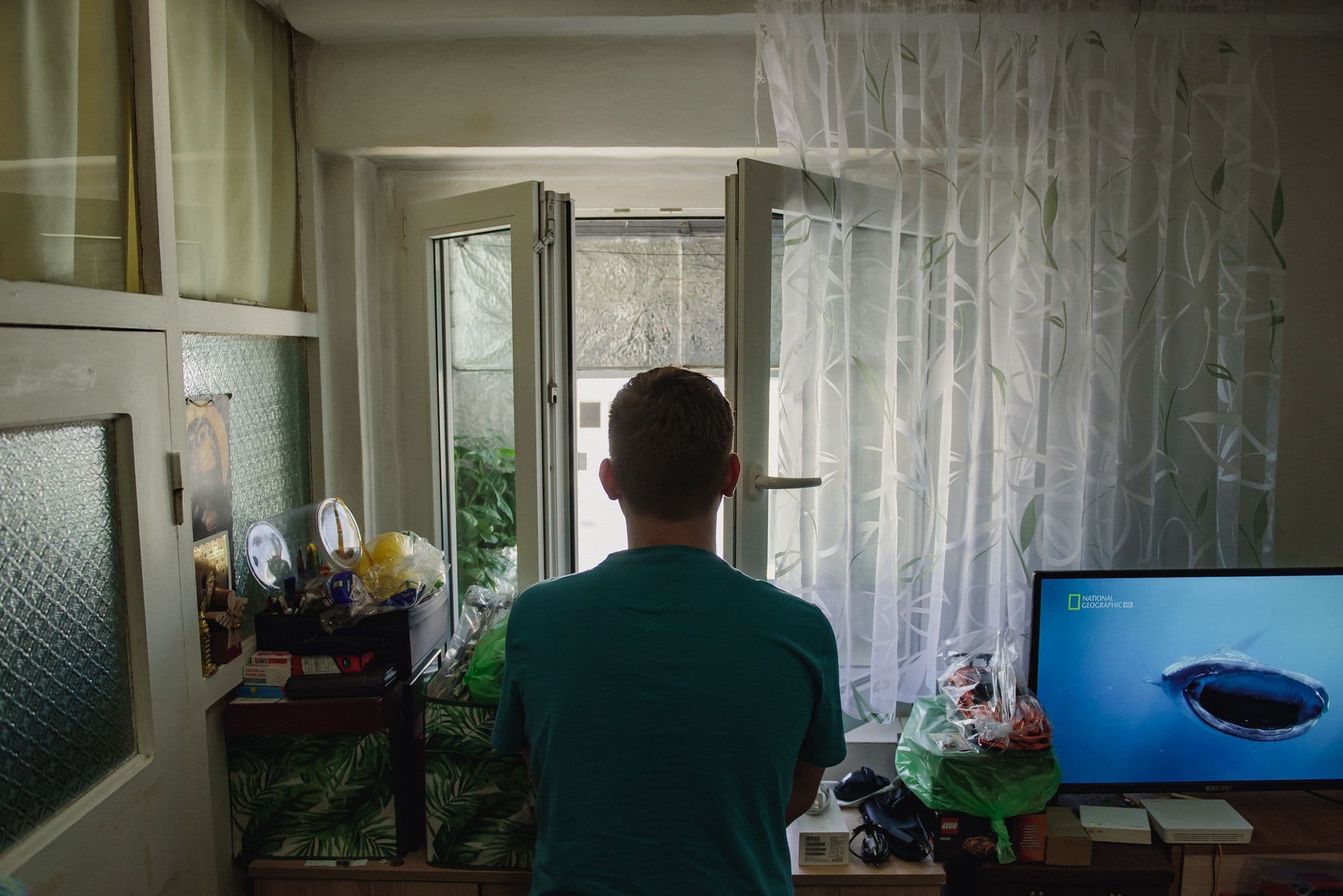 Cosmin, privind pe unicul gemuleț al camerei din garsoniera lui de 12 metri pătrați. Foto: Ioana Epure