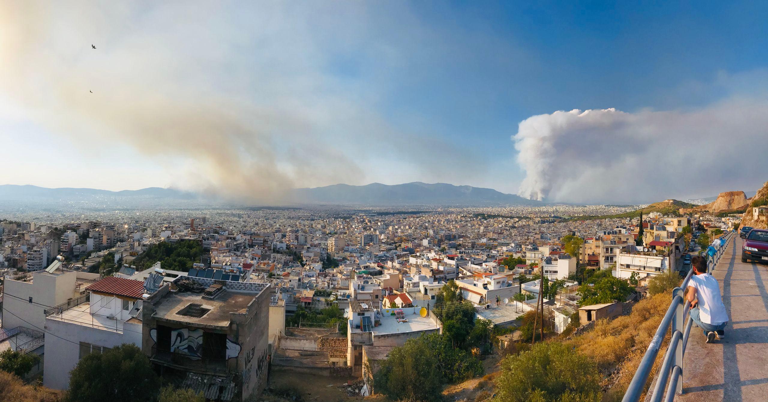 Incendiul din Varybombi (dreapta) și un incendiu nou izbucnit, în Ano Liosia (stânga) văzute de pe dealul Papandreou (aproape de Kypseli, un cartier central al Atenei)
