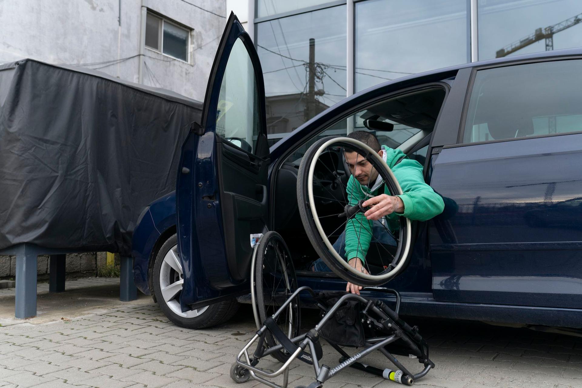 Angel se dă jos din mașină, la sediul fundației Motivation, în Bragadiru. Are nevoie de un loc de parcare special, mai lat decât cele obișnuite, pentru a se autotransfera în scaun. De multe ori, aceste locuri de parcare sunt ocupate în București. Foto: Andreea Câmpeanu