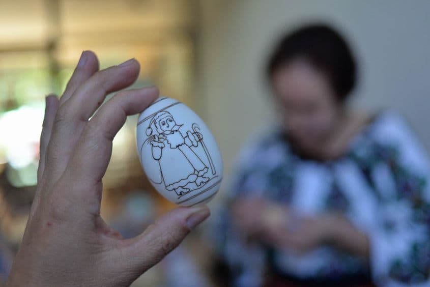 Ca să ne arate cum se pictează simbolurile de iarnă, artista a trasat pe loc, cu ceară neagră, conturul unui Moș Crăciun.