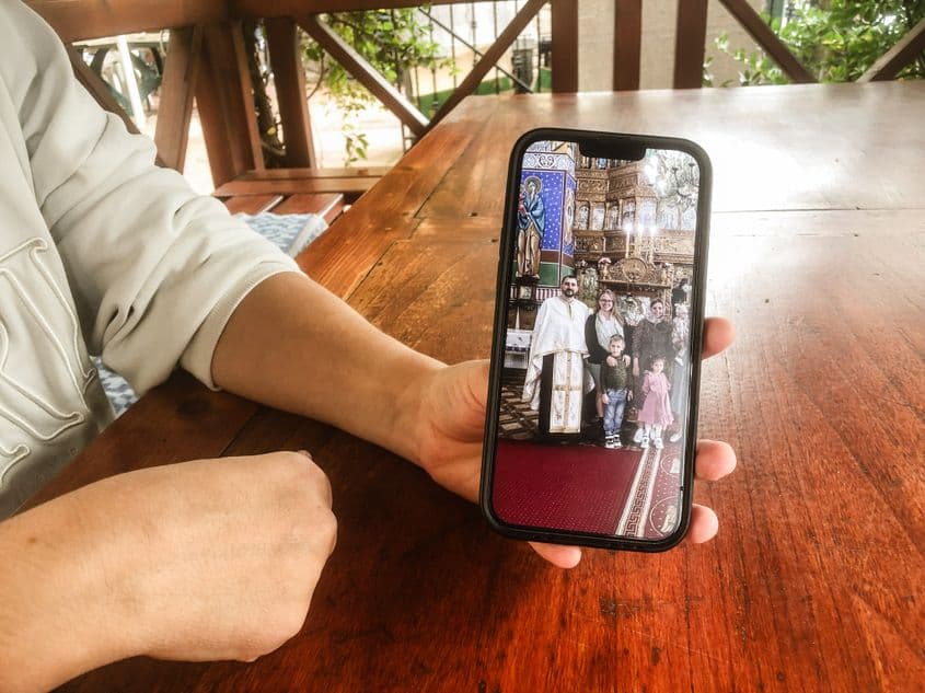 Katia, în foișorul din curte, cu o fotografie a preotului care i-a botezat copilul, la botezul altei mame din Băile Olănești. Spune că preotul e încă o persoană de ajutor și simte că e lângă ea, că poate să îl contacteze mereu. Foto: Andreea Soare