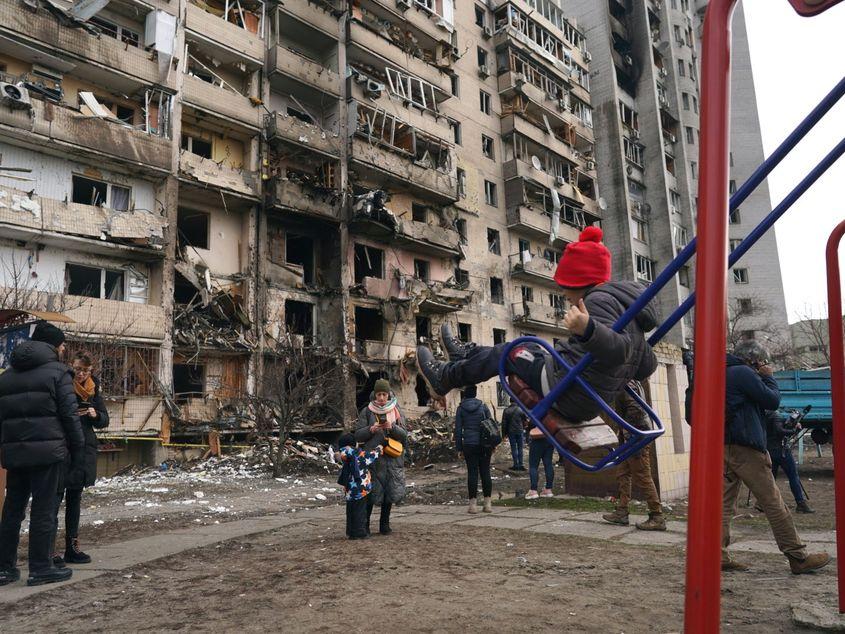 Kiev, Ucraina. O fetiță se dă în leagăn lângă un bloc distrus de căderea unei rachete rusești. Foto: Wolfgang Schwan - Anadolu Agency