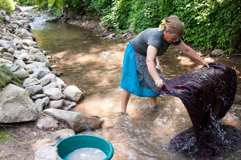 Tanti Maria își spală rufele la râu.