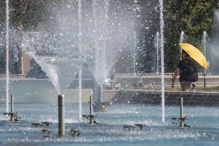 Un bărbat se protejează de razele solare cu ajutorul unei umbrele, în Piața Unirii din București, 17 iulie 2023. Foto: Inquam Photos/Sabin Cîrstoveanu