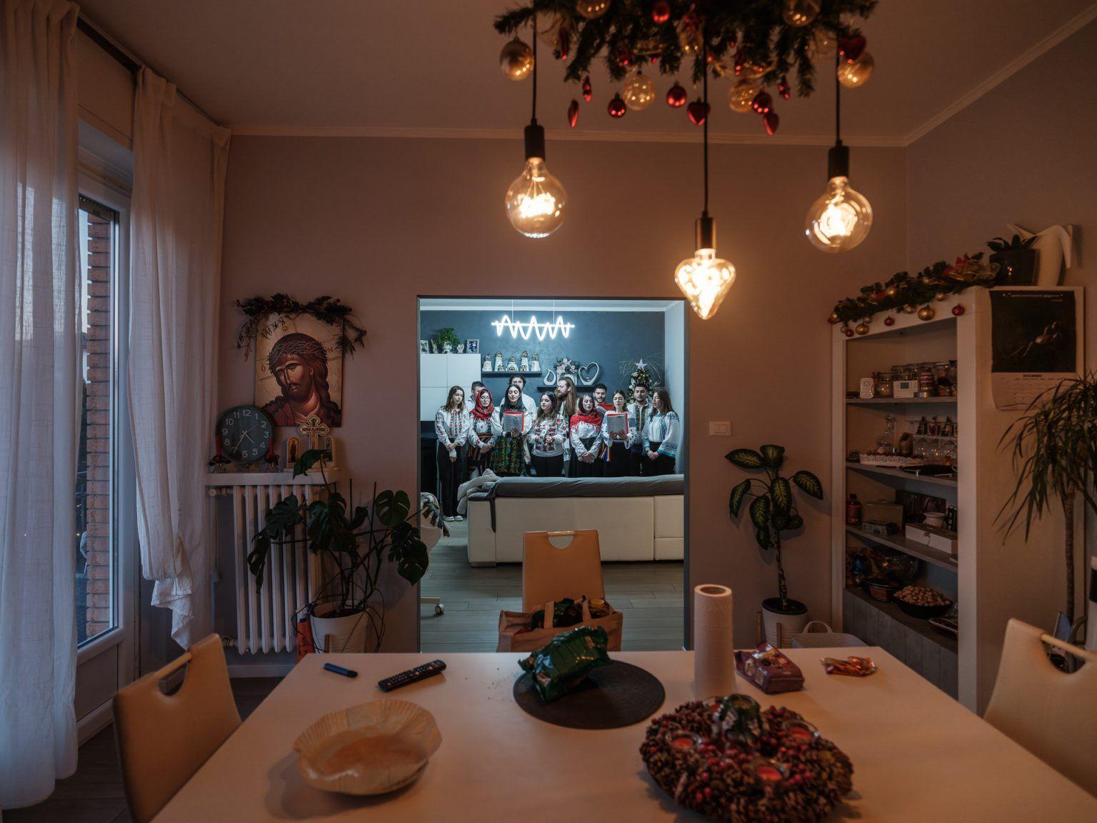 Un grup de tineri colindă la casa unei familii de români din Forlì. Au între 20 și 30 de ani și s-au născut sau au crescut în Italia, unde se află una dintre cele mai mari și mai vechi comunități de români din diaspora. Identitatea lor este modelată în primul rând de școala și societatea italiană, dar își doresc să păstreze și elemente din identitatea lor românească. Așa că, de Crăciun, merg să colinde în română – chiar dacă între ei vorbesc în italiană, care este, în realitate, limba lor nativă. 24 decembrie 2024. Foto: Cosmin Bumbuț