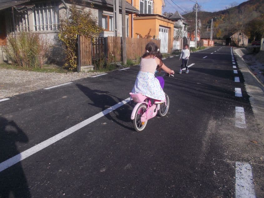 Cele două surori și prietenele lor se bucură că șoseaua din sat a fost asfaltată recent.