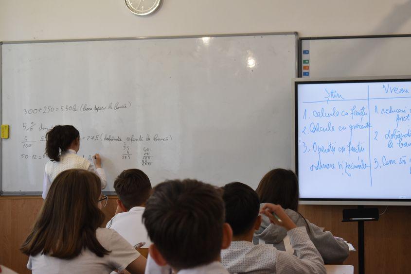 O elevă de clasa a cincea calculează dobânda unei sume depuse la bancă. Foto: Lavinia Niță / PressOne
