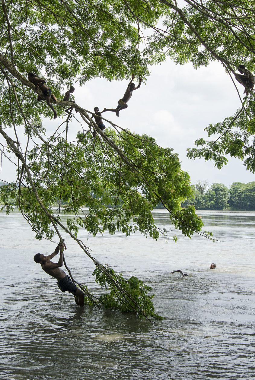 În Ambunti, în fața casei unde stau, copiii se adună la baie după școală.