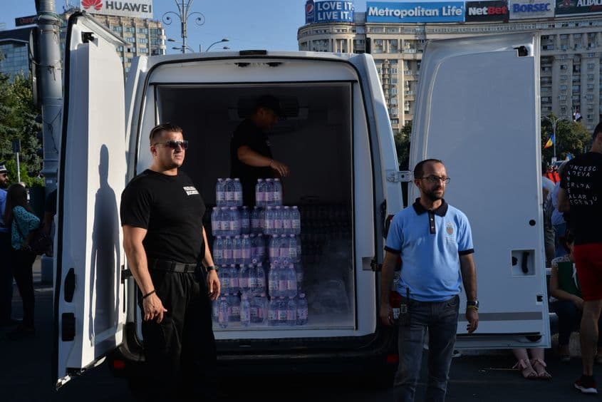 „Sigur nu vreți să luați? E rece și bună”, încerca distribuitorul să îi convingă pe protestarii din jur, fără a-și șterge zâmbetul politicos de pe față. „Mulțumesc, mi-am luat singur”, au venit scurt și răspunsurile câtorva trecători Foto: Maria Tufan