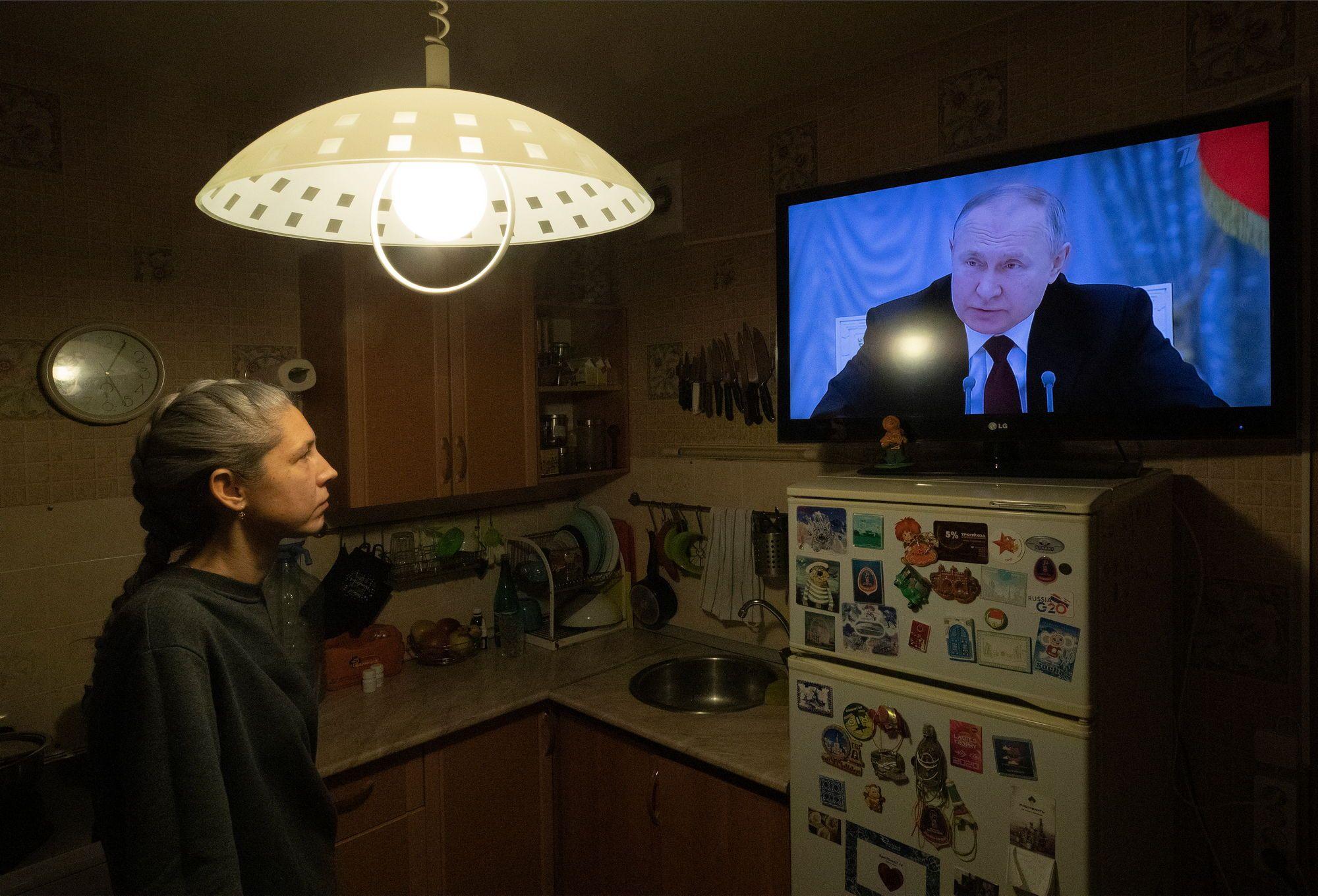O femeie din Sankt Petersburg privește în timp ce președintele Vladimir Putin ține un discurs pe tema Ucrainei. Foto: EPA/Anatoly Maltsev