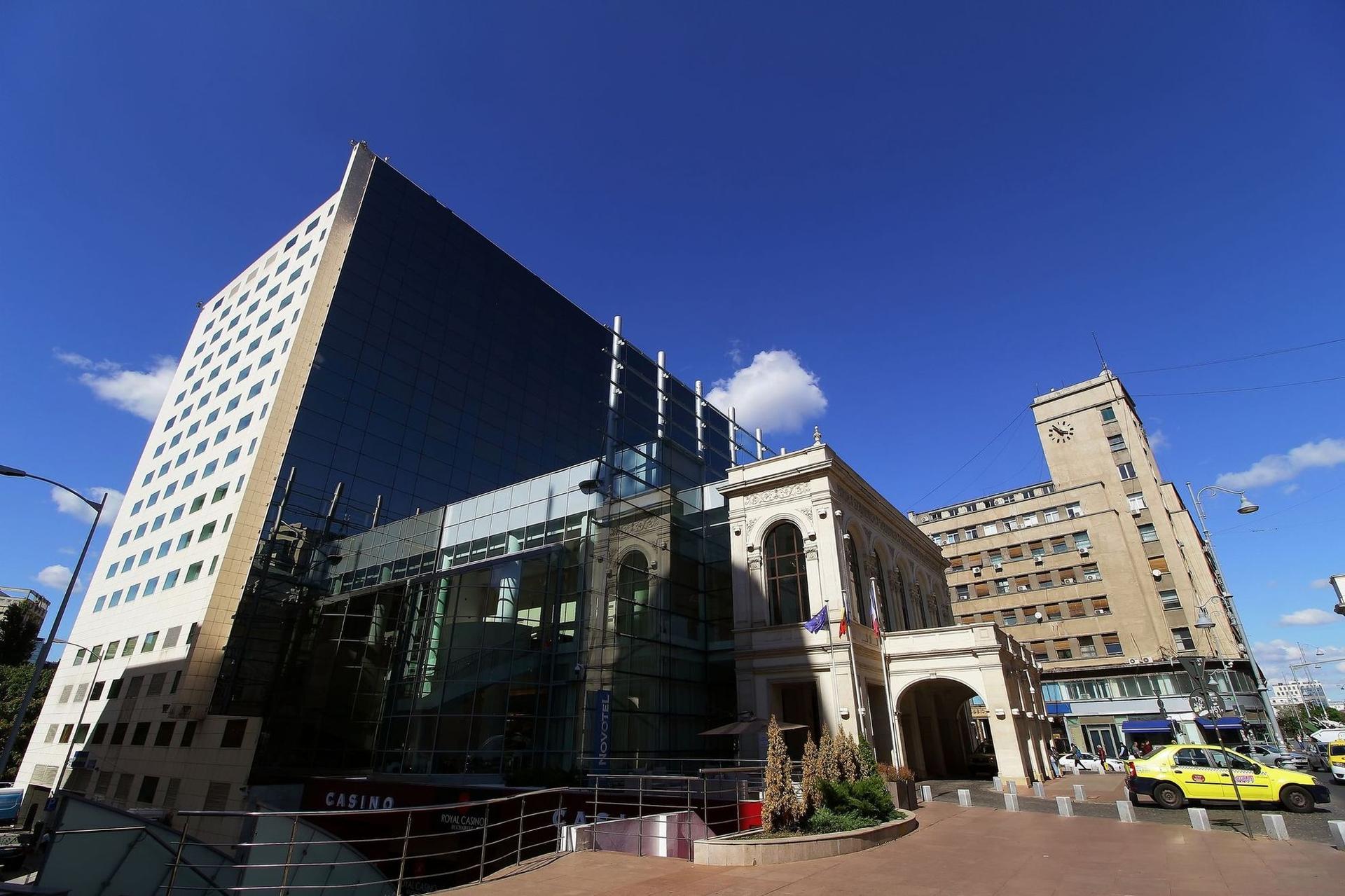 În două secole, fostul Teatru Național a dispărut și apoi reapărut doar sub forma unei fațade. În fața sa stau, cum altfel, taxiurile. Foto: © <a target="_blank" href="https://www.dreamstime.com/lcva_info">LCVA</a> | <a target="_blank" href="https://www.dreamstime.com/photos-images/taxi-bucharest.html">Dreamstime.com</a>