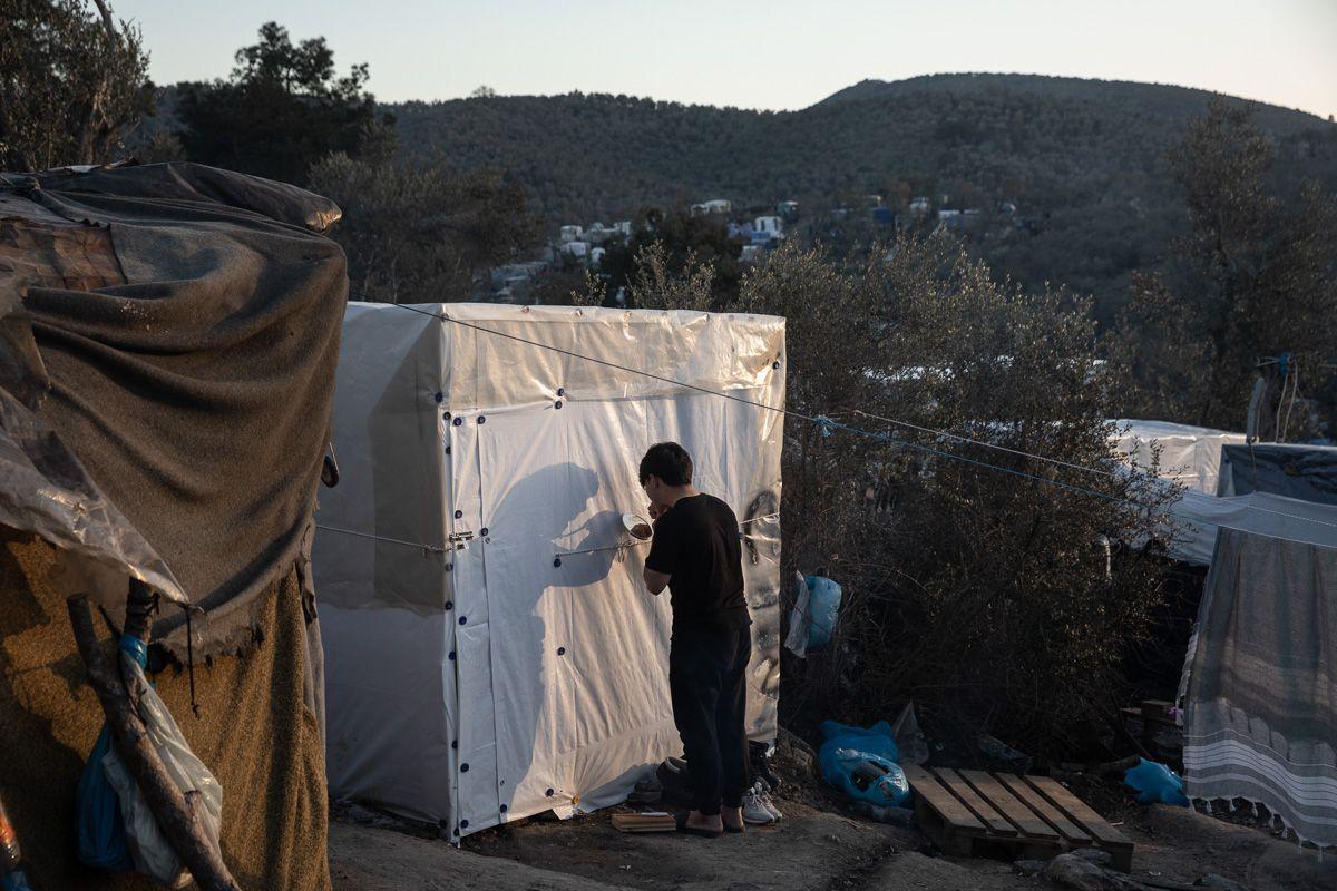 Un migrant din Afganistan își rade barba în timp ce se uită într-o oglindă din fața colibei sale din tabăra de refugiați Moria, de pe insula Lesbos, Grecia, la 11 februarie 2020. Foto: Konstantinos Tsakalidis