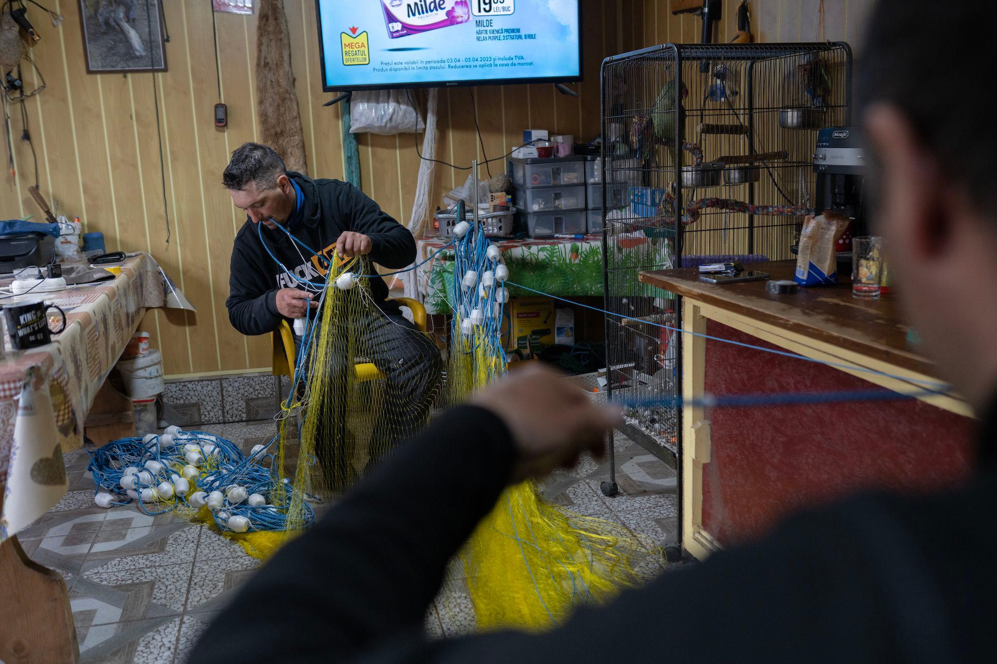 Mirel Efimov, fiul lui Nicu Efimov, ambii pescari, pregătește plasa cu care vor pescui. La început de aprilie erau ultimele zile în care era permis pescuitul la scrumbie. Ulterior, se va intra în perioada de prohibiție. Foto: Andreea Câmpeanu