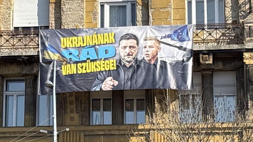 Un banner care îl afișează pe Volodimir Zelenski și pe Péter Magyar în Piața Deák, Budapesta, punctul de adunare pentru Marșul Național al Partidului Tisza, pe 15 martie 2026.
Foto: Vilmos Bábel/444