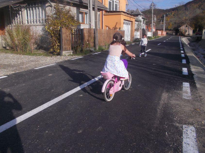 Cele două surori și prietenele lor se bucură că șoseaua din sat a fost asfaltată recent.