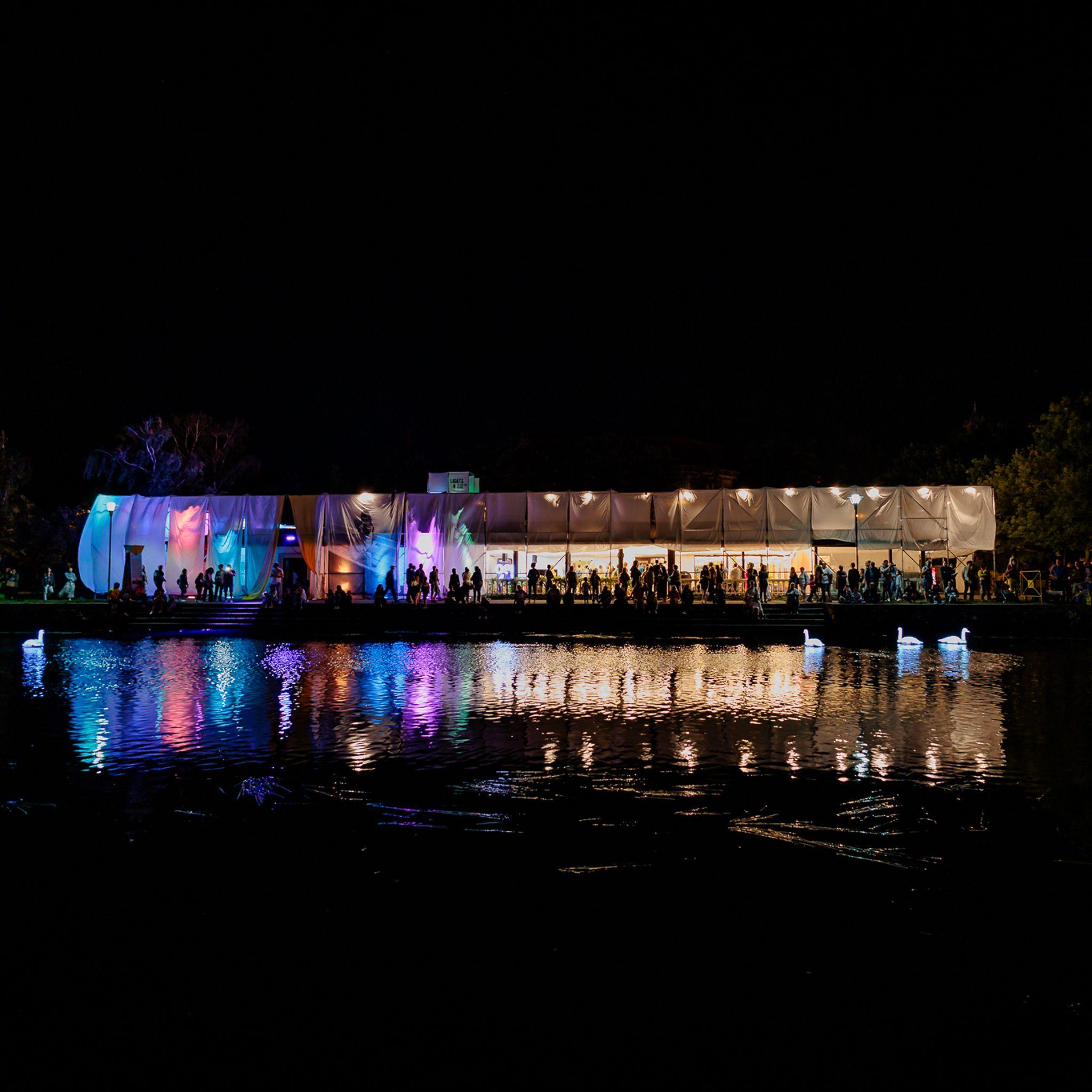 Oameni pe malul Begăi pentru instalația Electric Swan Ensemble. Electric Swan Ensemble, care poate fi admirată în fiecare seară de la 21.00 pe Bega. Oamenii se adună din timp pentru a prinde locurile cele mai bune pe trepte și asistă la cum se pun lebedele pe apa. Pe măsură ce 12 lebede artificiale alunecă cu eleganță, luminile și sunetele se contopesc cu mișcarea, conturând un tablou cu adevărat special.