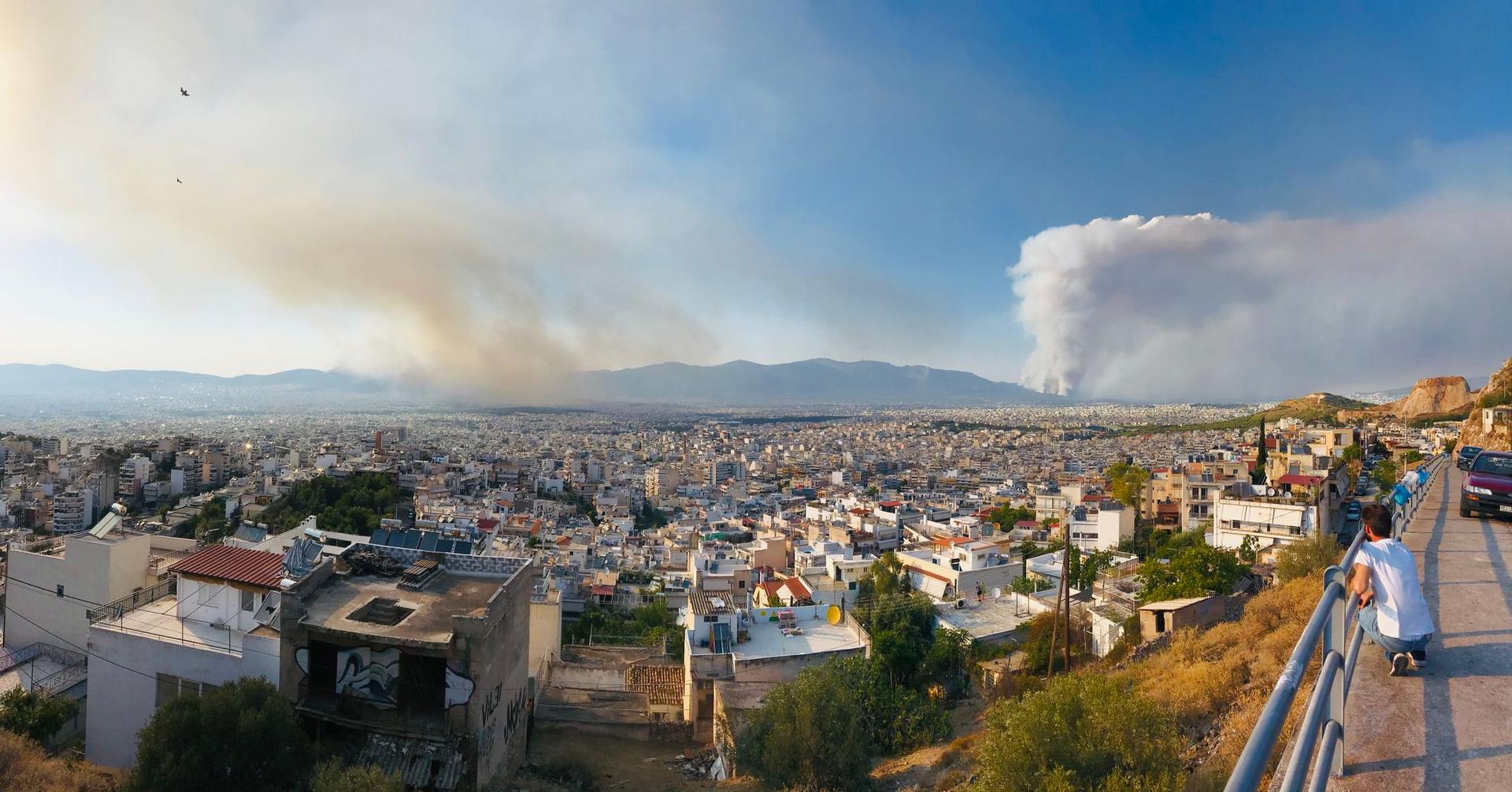 Incendiul din Varybombi (dreapta) și un incendiu nou izbucnit, în Ano Liosia (stânga) văzute de pe dealul Papandreou (aproape de Kypseli, un cartier central al Atenei)
