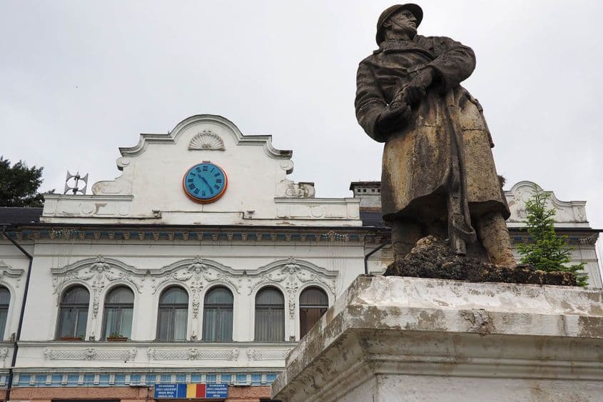 În fața Primăriei din Bocșa, un soldat de piatră scoate cuiul unei grenade…