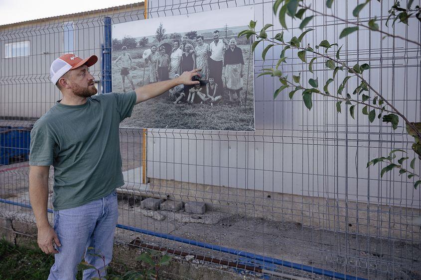 <em>George Cățean arată spre părinții și bunicii din fotografie, alături de vecinii lor sași și maghiari. Foto: Eli Driu</em>