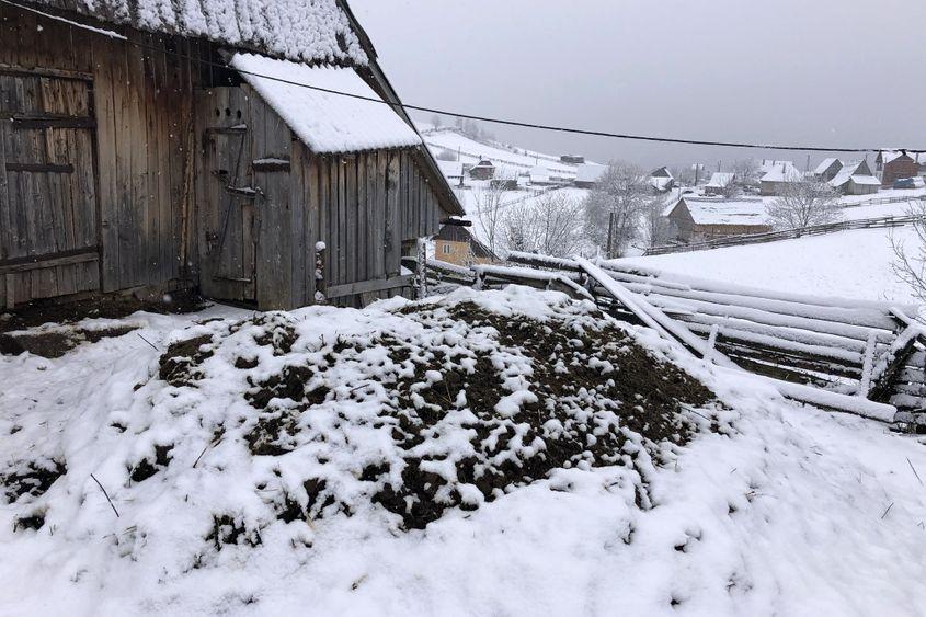 Veceul lipit strategic de grajd, topit în peisaj lângă muntele de îngrășământ natural.