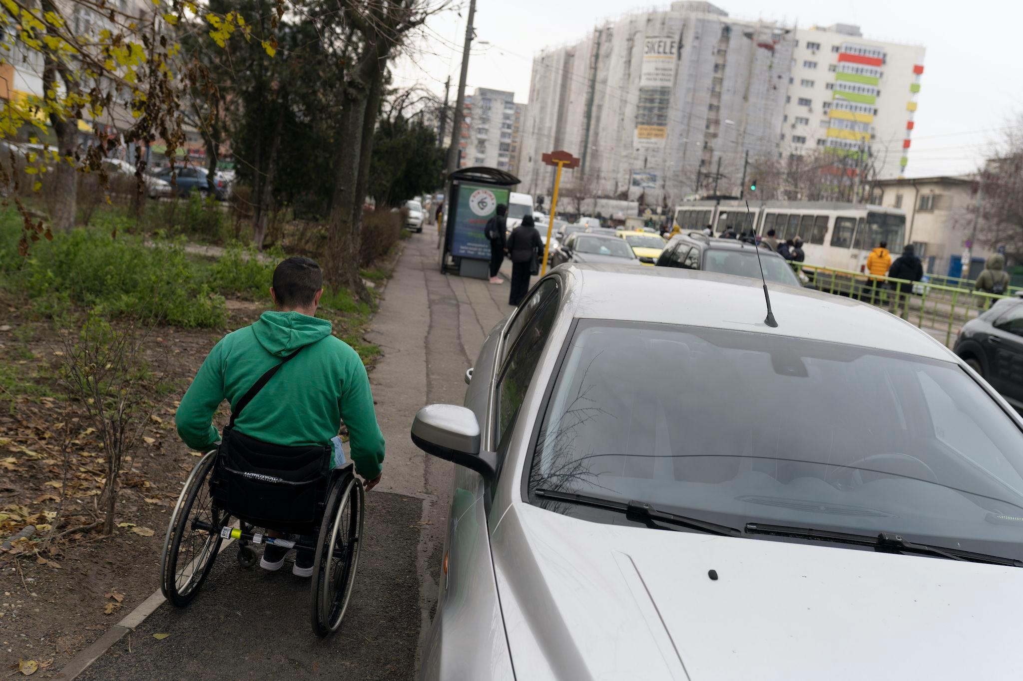 Unui om în scaun rulant precum e Angel îi e aproape imposibil să se deplaseze pe străzile din București, din cauza mașinilor parcate ilegal. Foto: Andreea Câmpeanu