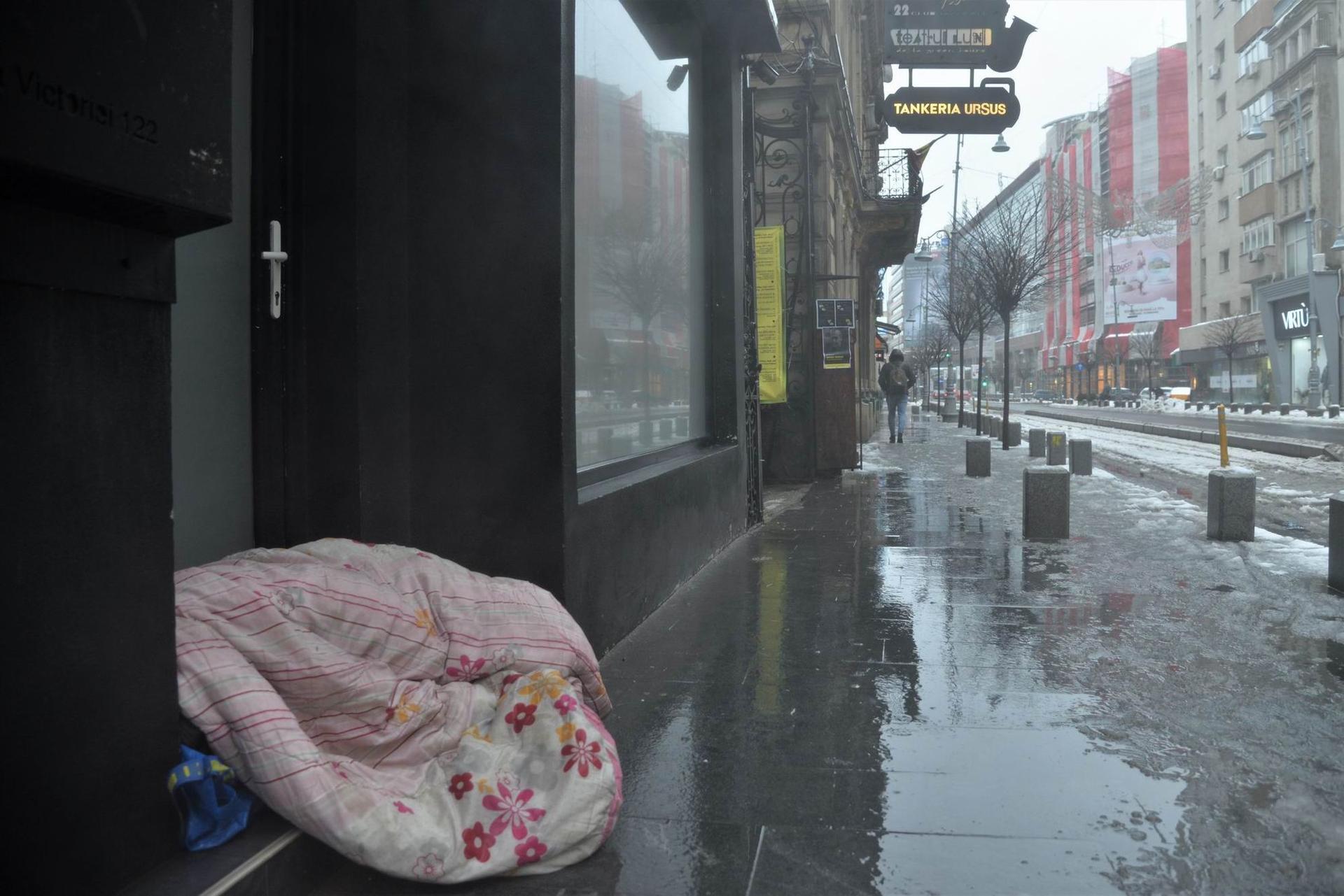 Un om fără adăpost doarme pe trotuarul de pe Calea Victoriei. Foto Lucian Muntean