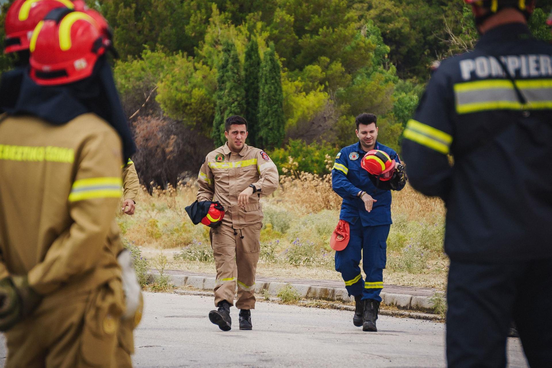 Doi pompieri eleni participă la un exercițiu de stingere a incendiilor în Atena. Foto: Ioana Epure