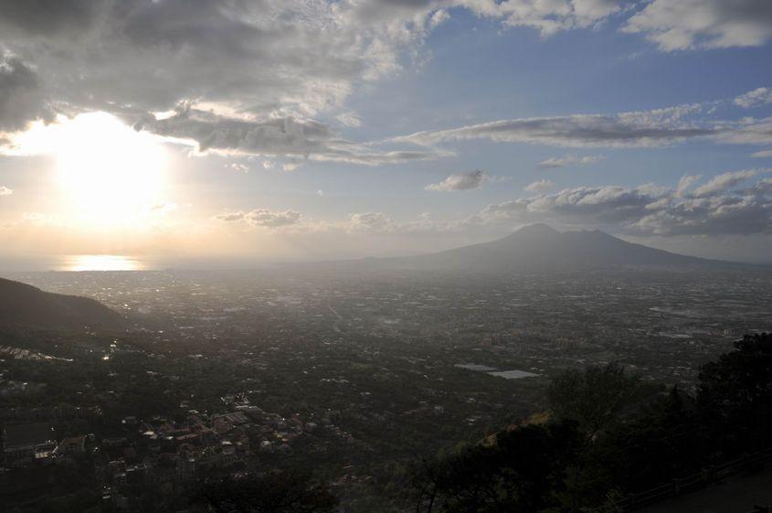 Sub un cer învolburat, reflexia soarelui sclipește peste Golful Napoli, aflat la poalele Vezuviului. Foto: Lucian Muntean